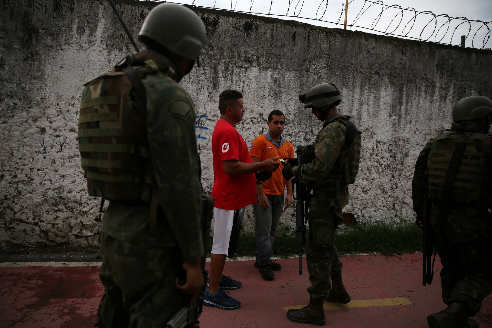 20.fev.2018 - Moradores da favela Kelson's, na zona norte do Rio de Janeiro, passam por ponto de inspeção das Forças Armadas. As entradas da comunidade foram ocupadas pelos militares do Exército. Ao menos quatro suspeitos foram presos até o final da manhã - Pilar Olivares/Reuters