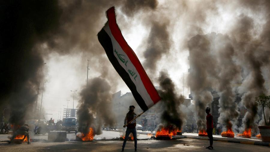 Manifestantes com a bandeira do Iraque, em Najaf, durante dia de protestos no país - Alaa al-Marjani/Reuters