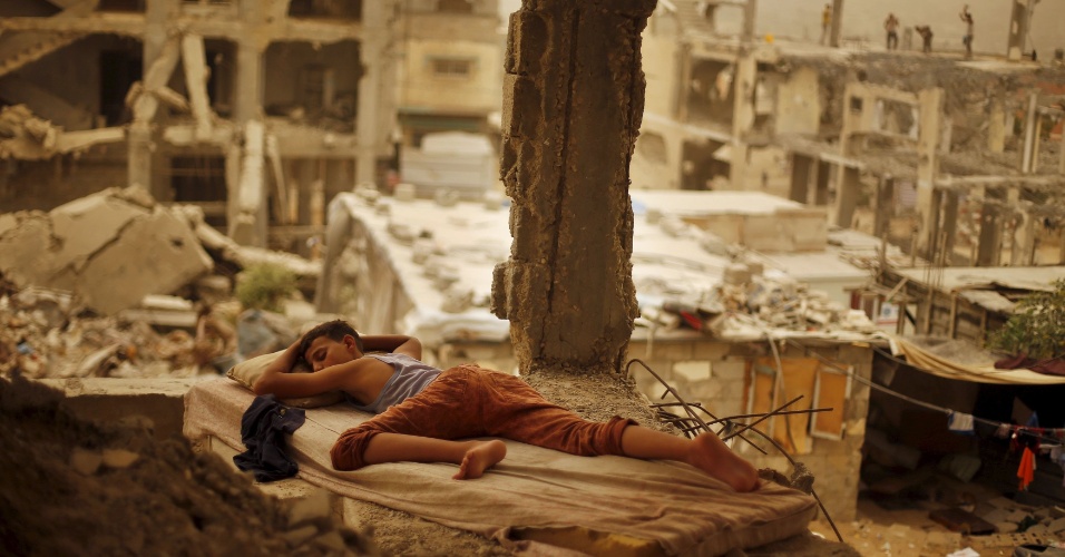 8.set.2015 - Jovem palestino dorme sobre colchão em casa destruída por um bombardeio israelense, durante confrontos com o Hamas em 2014, em Gaza