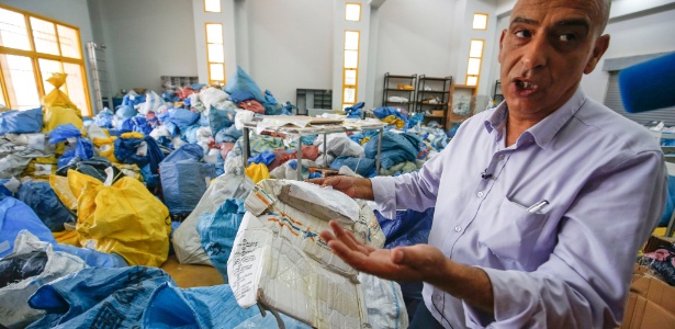 Ramadan Ghazawi, funcionário dos correios da Cisjordânia em Jericó, mostra um dos pacotes danificados entregues por Israel - ABBAS MOMANI / AFP