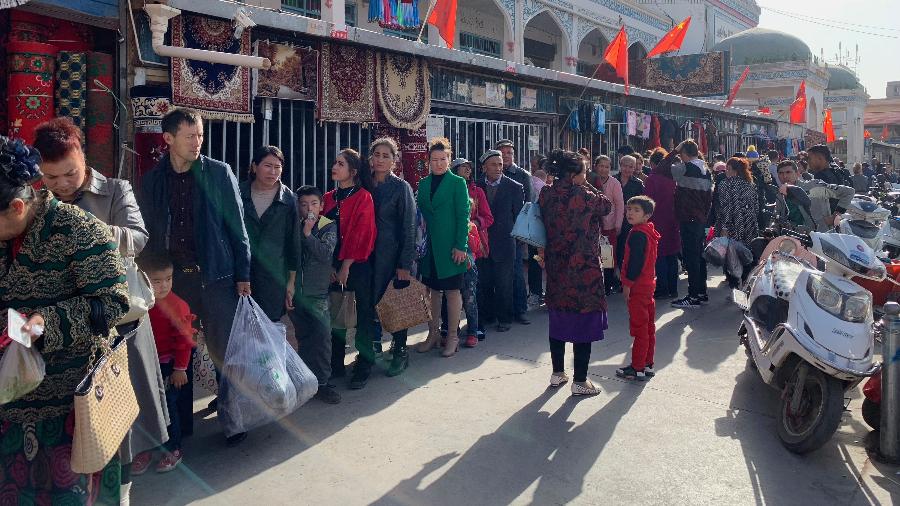 Consumidores fazem fila para verificação de documentos nos arredores do mercado de Kashgar na região de Xinjiang, na China - Paul Mozur/The New York Times