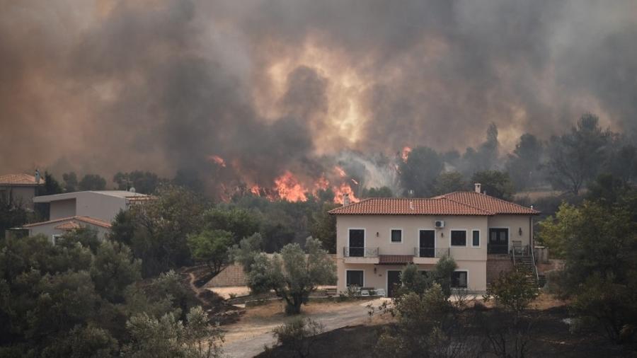 Fogo se aproxima de casa no vilarejo de Afidnes, a 30km de Atenas, na Grécia. Centenas de bombeiros lutam para extinguir chamas - Louisa Gouliamaki/AFP