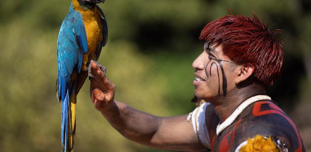 Manapu, um homem Yawalapiti, segura uma arara-azul e amarela durante o Kuarup