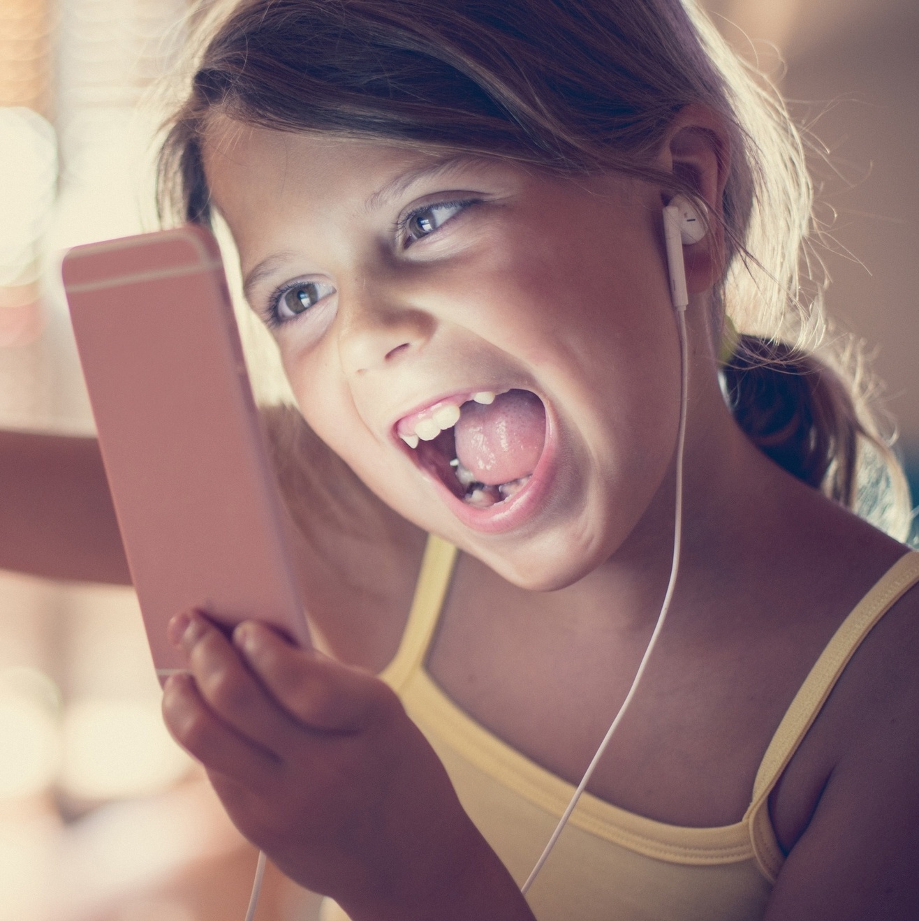 Lazer e entretenimento infantil. tecnologia e dispositivos digitais na  educação de crianças. garota feliz e sorridente jogando jogos no celular.