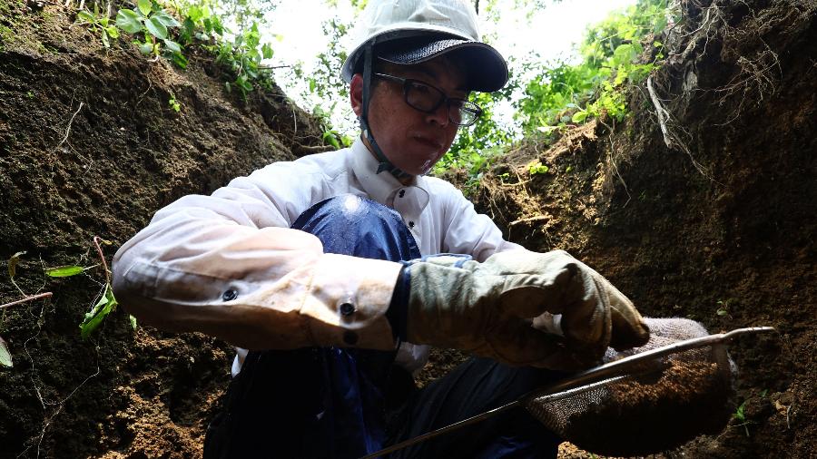Rebun Kayo procura fragmentos de ossos descobertos em um sítio na Ilha de Ninoshima Rebun Kayo procura fragmentos de ossos descobertos em um sítio na Ilha de Ninoshima