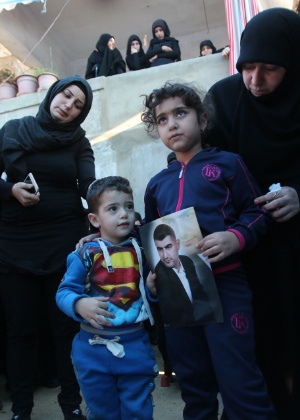 Ali e Malak (à dir.) seguram a foto do pai, Adel Termos, morto ao se jogar diante de um homem-bomba em Beirute - Mahmoud Zayyat/AFP