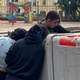 Pessoas vasculham lixo em busca de produtos de camelô levados pela enchente no centro histórico de Porto Alegre