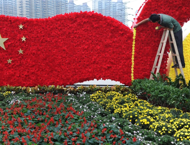 Trabalhador monta bandeira chinesa criada com flores para celebrar o Dia Nacional da China, em Hefei - AFP