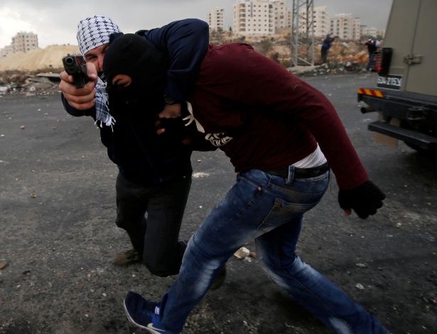 13.dez.2017 - Agente israelense, infiltrado em um protesto palestino, aponta arma para fotógrafo da agência Reuters durante manifestação próximo a Ramallah, na Cisjordânia - REUTERS/Mohamad Torokman