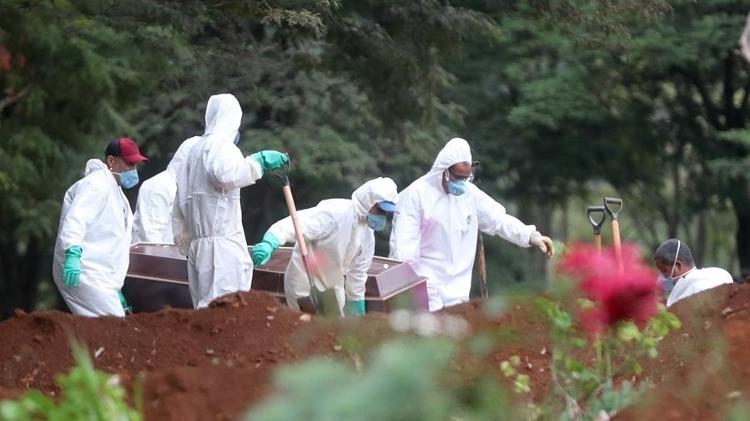 Funcionários do serviço funerário enterram corpo de uma vítima do novo coronavírus no cemitério da Vila Formosa, em São Paulo - Fernando Bizerra/EFE