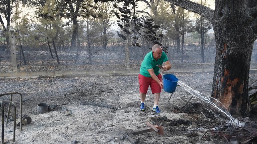 Homem joga água em área após incêndio na região de Pumarejo, norte da Espanha; onda de calor, responsável por temperaturas acima dos 43ºC, agrava queimadas no país e em outras partes da Europa - MIGUEL RIOPA/AFP