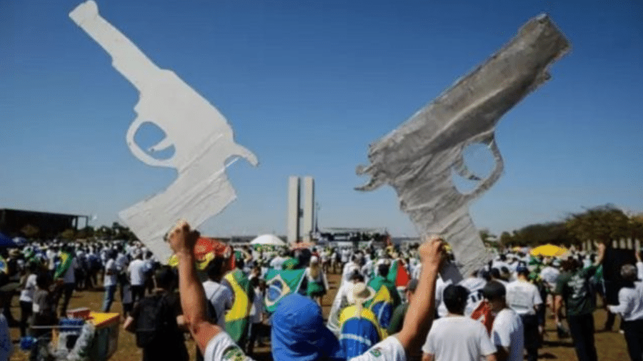 Homem com armas de papelão em comício - GETTY IMAGES