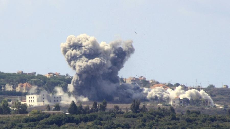 Fumaça sai do local de um ataque aéreo israelense na vila libanesa de Tayr Harfa, perto da fronteira Líbano-Israel, em 23 de setembro de 2024