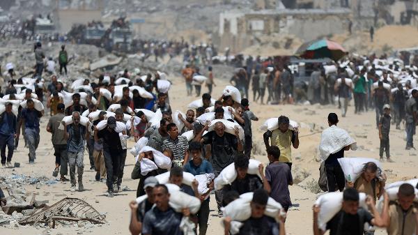 27.jul.2025 - Palestinos com alimentos após ajuda humanitária; mais de 130 pessoas morreram de fome em Gaza