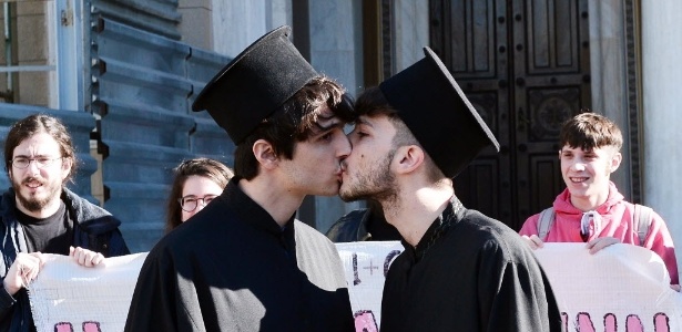 Ativistas dos direitos gays vestidos como sacerdotes ortodoxos se beijam ao lado da igreja Metropolitan, em Atenas, na Grécia - Louisa Gouliamaki/AFP 