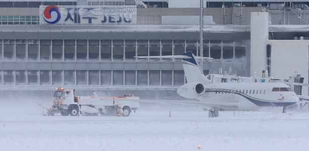 24.jan.2016 - Neve é retirada de pista do aeroporto de Jeju, na Coreia do Sul