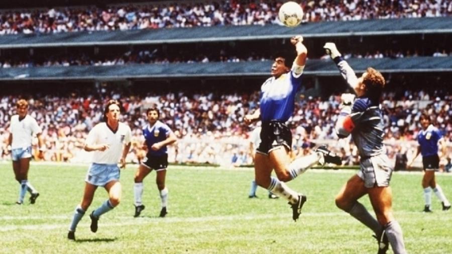 Maradona faz o seu lendário gol de mão contra a Inglaterra em 1986. Aras tenta ser "a mão de Deus" para Bolsonaro. - Foto:  Bongarts/Getty Images