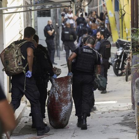 06.05.2021 - Policiais civis carregam baleado durante operação na favela do Jacarezinho, no Rio, que deixou 27 mortos