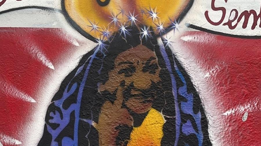 Prefeitura de SP remove grafite de Nossa Senhora de muro da EMEI Santos Dumont; na imagem, ela aparece mostrando o dedo do meio - Reprodução