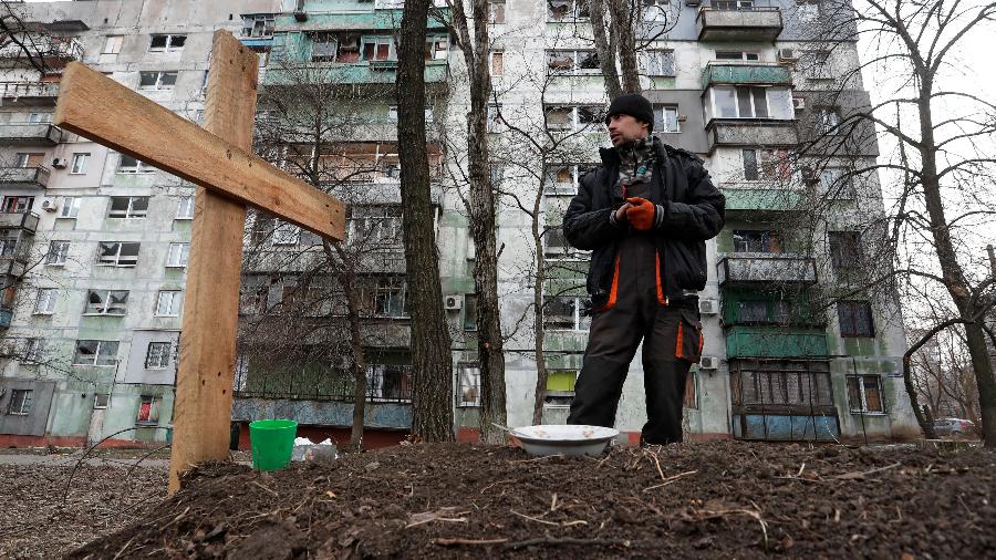 O morador local Pavel, 42, ao lado do túmulo de seu amigo Igor, que foi morto por um bombardeio enquanto viajavam juntos em um carro durante o conflito Ucrânia-Rússia, em uma área residencial na cidade portuária sitiada de Mariupol - Alexander Ermochenko/Reuters