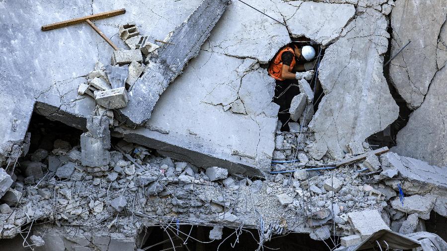 Membro da defesa civil palestina em um prédio atingido por bombardeio israelense no sul da Faixa de Gaza, em 19 de outubro de 2023