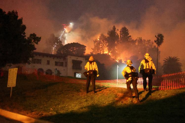 08.jan.25 - Um helicóptero realiza um lançamento de água, enquanto fumaça e chamas sobem do incêndio Sunset nas colinas com vista para o bairro de Hollywood em Los Angeles, Califórnia, EUA