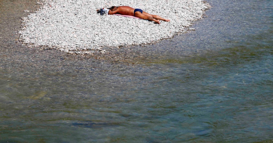 23.jul.2015 - Homem toma banho de sol, na margem do lago Isar, em Munique (Alemanha)