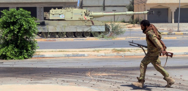 Soldado das forças líbias passa ao lado de um tanque em Sirte - Mahmud Turkia/ AFP 