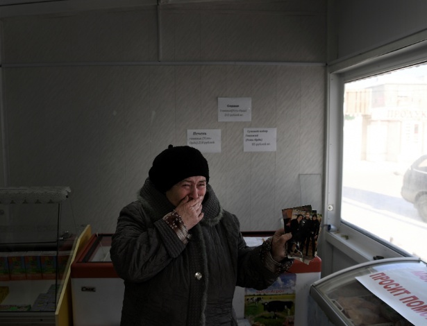 Zoya Mukhamadeyeva chora enquanto segura foto de seu filho, Renat, em Irkutsk, na Rússia - James Hill/The New York Times