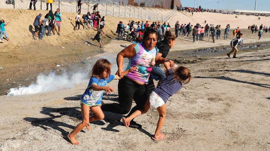 25.nov.2018 - Família de migrantes hondurenhos foge do gás lacrimogêneo na fronteira entre os EUA e o México, em Tijuana - Kim Kyung-Hoon/Reuters