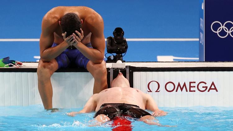 O alemão Lukas Maertens descansa após conquistar a primeira medalha de ouro na natação das Olimpíadas, no último dia 27; no fundo, o brasileiro Guilherme Costa, que terminou em 5, lamenta a derrota