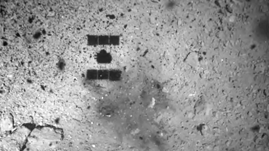 Foto tirada pela câmera ONC-W1 do asteroide Ryugu e recebida da sonda Hayabusa2 mostra a sombra da espaçonave japonesa Hayabusa2 (no topo à esquerda) sobre o asteroide Ryugu antes de aterrissar - AFP