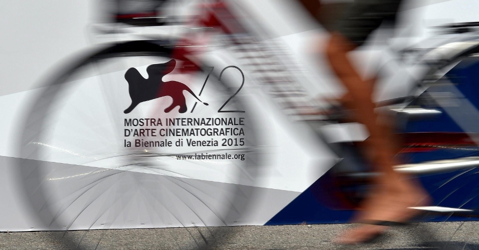 31.ago.2015 - Homem em uma bicicleta passa ao lado do cartaz da 72º edição do Festival de Cinema de Veneza, na Itália