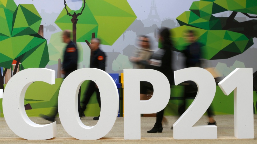 Participantes passam pelo logo da COP 21 - a Conferência do Clima das Nações Unidas - realizada em Paris há três anos - Stephane Mahe/Reuters
