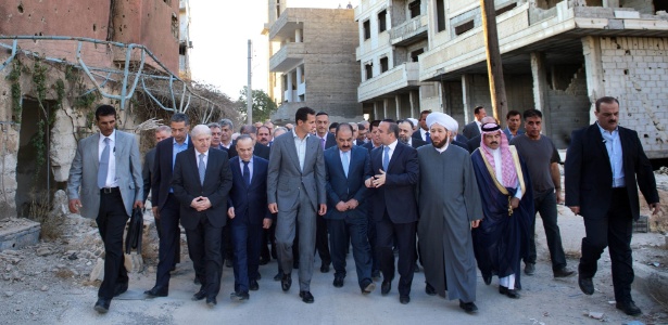 Foto divulgada pela agência de notícias oficial da Síria, Sana, mostra o presidente sírio Bashar al-Assad (no centro) caminhando em uma rua na área controlada pelo governo de Daraya, em Damasco - AFP/ SANA
