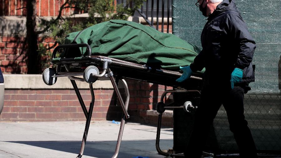 Trabalhador transporta corpo de pessoa morta em hospital no Brooklyn, em Nova York, em meio à pandemia de coronavírus - BRENDAN MCDERMID