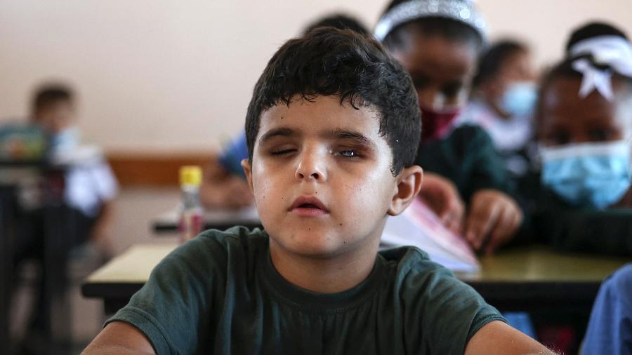 17.ago.2021 - O aluno palestino Mohammed Shaban senta-se ao lado de colegas na escola em Beit Lahia, no norte da Faixa de Gaza - Mahmud Hams/AFP