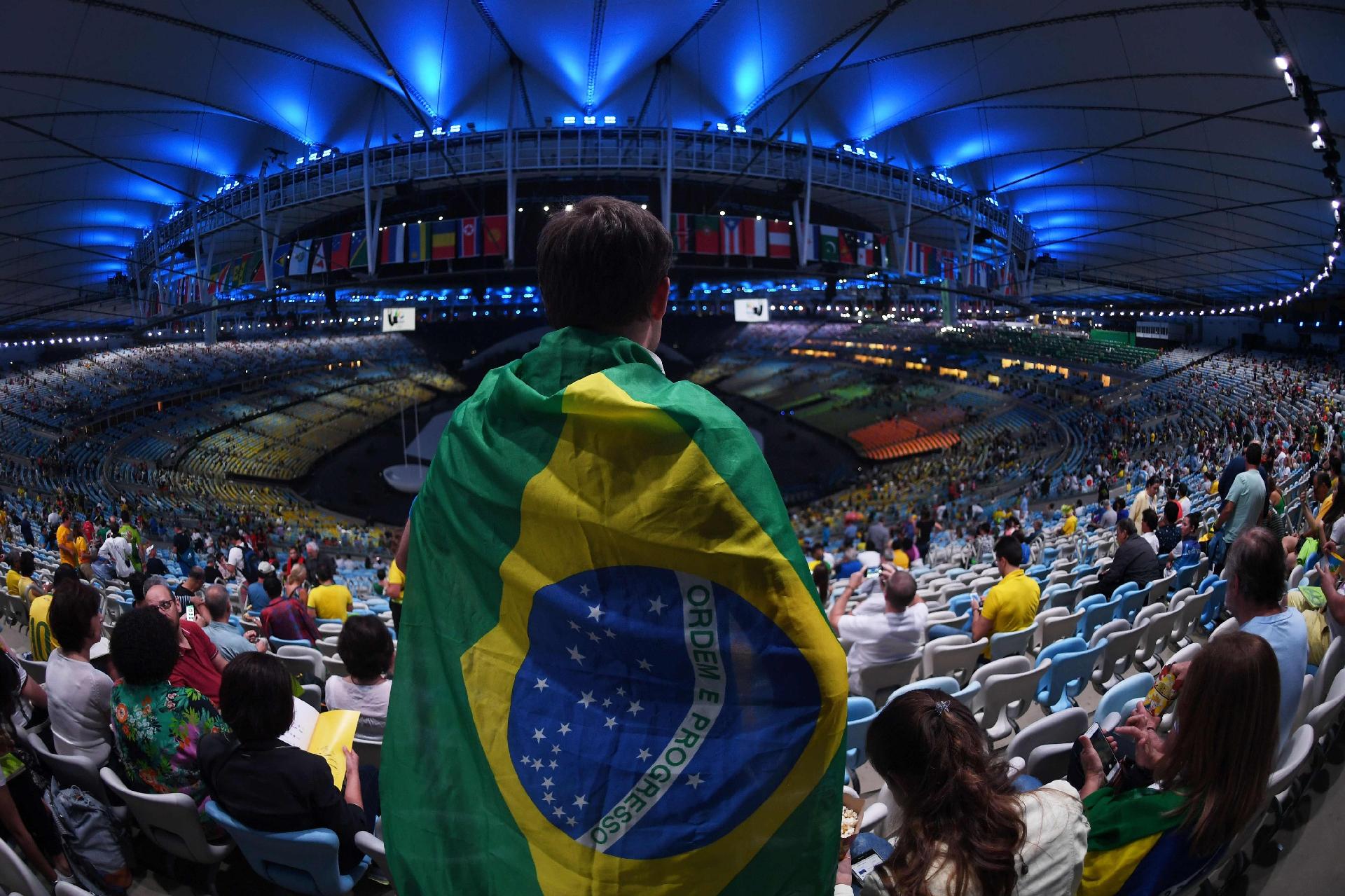 Enrolado em bandeira do Brasil, torcedor aguarda o início da cerimônia - CHRISTOPHE SIMON/AFP