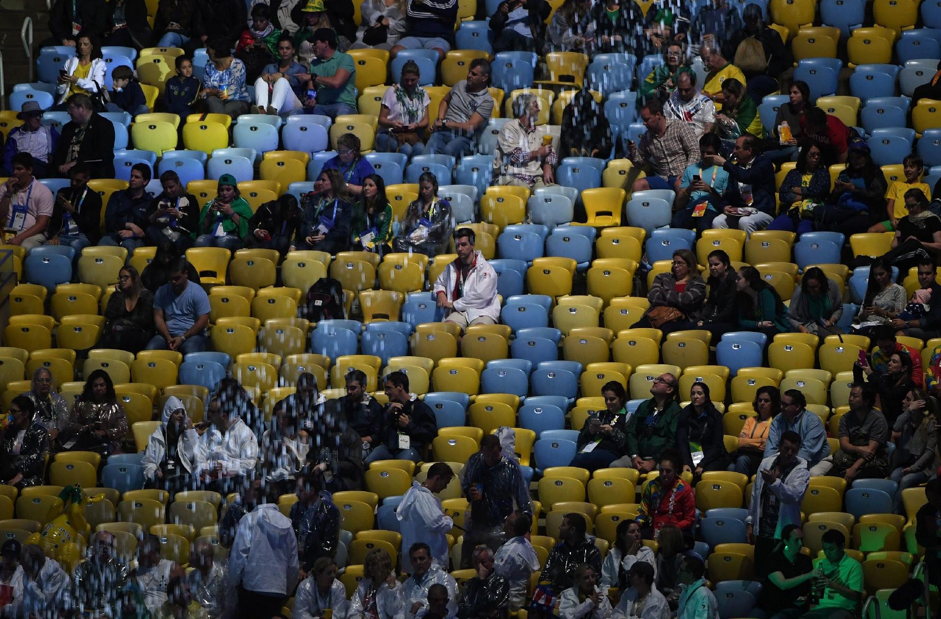 Ainda com muitos assentos vazios, torcedores aguardam o início da cerimônia de encerramento da Olimpíada - GREG BAKER/AFP