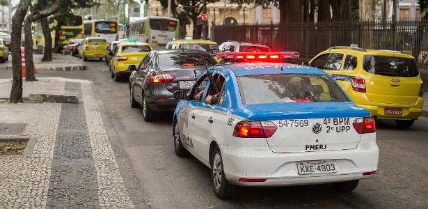Policiais da PM seguram fuzis para fora da viatura em rua engarrafada na Lapa no centro do Rio de Janeiro