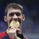 Michael Phelps morde a medalha de ouro conquistada no revezamento 4x100 m medley - Fei Maohua/Xinhua