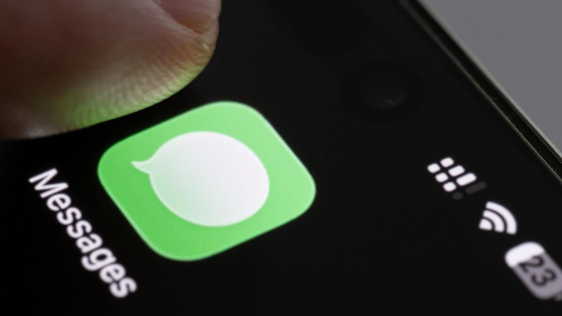 Dedo tocando no ícone do app Mensagens (Messages), da Apple, em um iPhone - undefined
