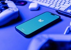 Como mudar a ordem das respostas em posts do Bluesky [iPhone e web] - App Bluesky no iPhone ao lado de um controle de PS5, AirPods e teclado