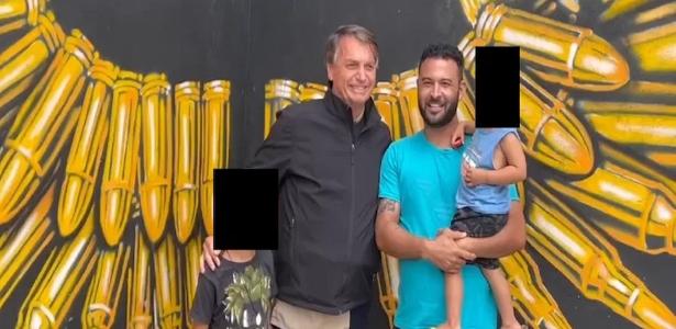 Bolsonaro tira foto com crianças à frente de painel com pintura de balas de armas de fogo 