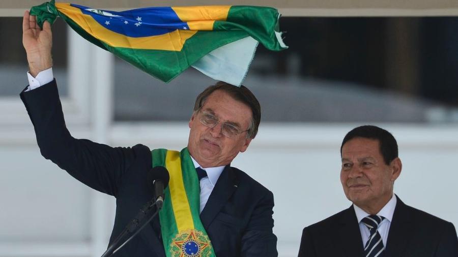 Bolsonaro e o vice-presidente Hamilton Mourão exibem uma bandeira nacional durante discurso no parlatório do Palácio do Planalto - Marcelo Camargo/ABr