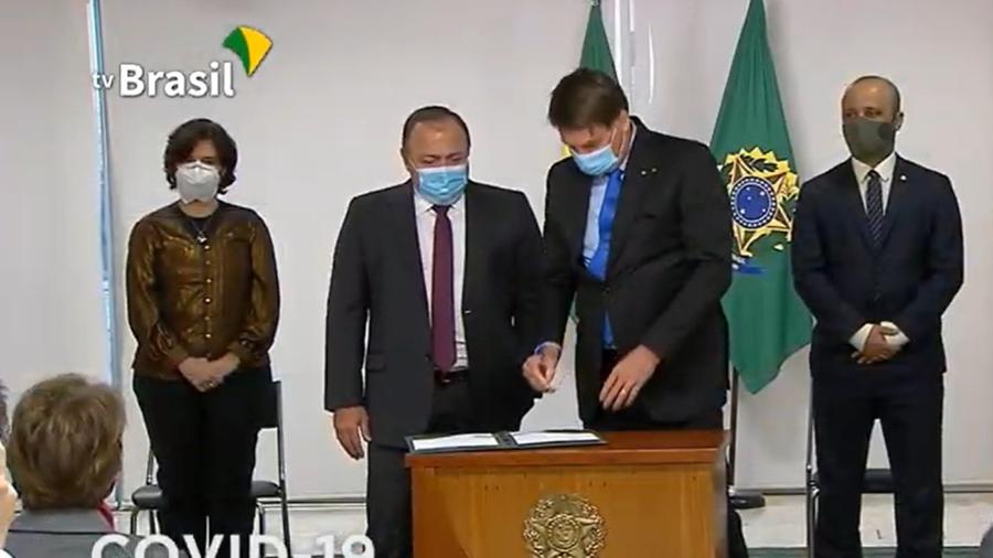 Jair Bolsonaro e o ministro interino da Saúde, Eduardo Pazuello, na assinatura da MP para produção de vacina contra covid-19 [Reprodução/TV Brasil]  - Reprodução/ TV Brasil