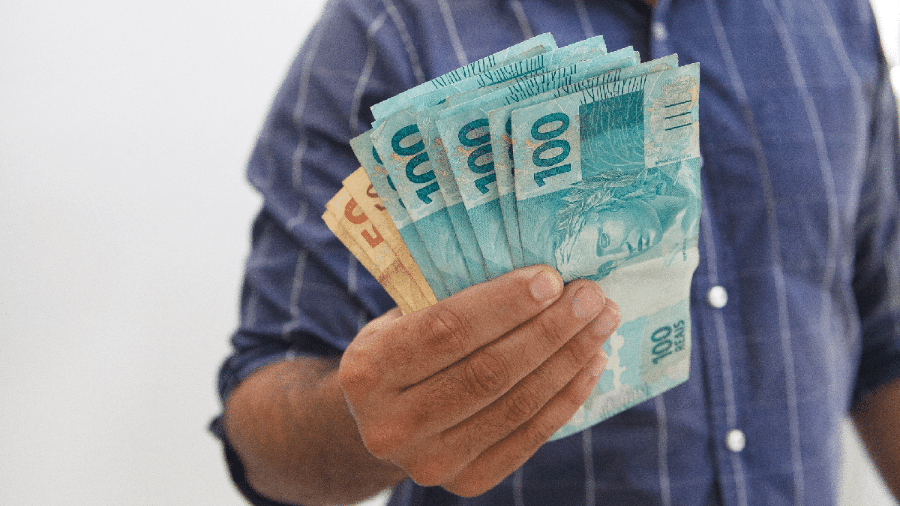 Homem segura notas de cem e cinquenta reais, a sétima moeda a ser implantada no Brasil - Divulgação