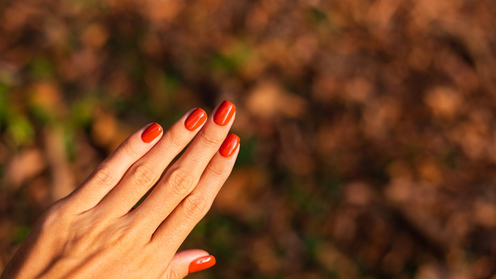 Imagem de uma mão de mulher com manicure laranja
 - undefined