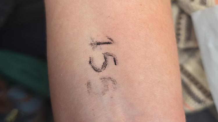 Ela tem o número 155 no braço, algo normal na fila; todo mundo tem um número que é para existir um certo controle, que não funciona sempre. Ela tem o número 155 no braço, algo normal na fila; todo mundo tem um número que é para existir um certo controle, que não funciona sempre.
