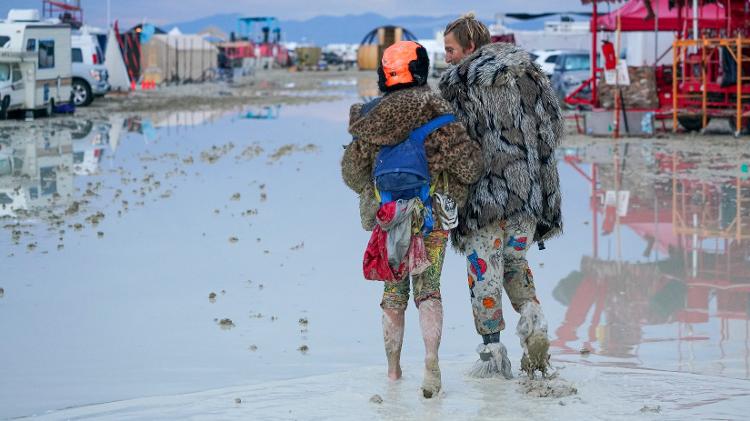 Casal caminha pela lama no Burning Man 2023